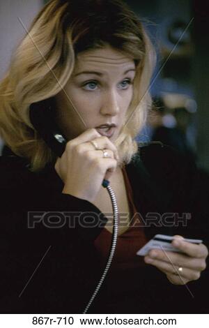Stock Image - Businesswoman talking on a pay phone. Fotosearch