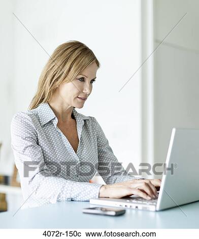 Stock Image - Businesswoman using a laptop at home. Fotosearch