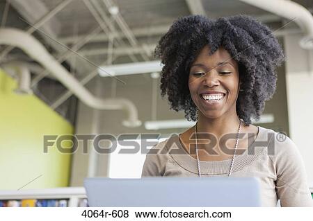 Stock Photo - Businesswomen using laptop in office. Fotosearch