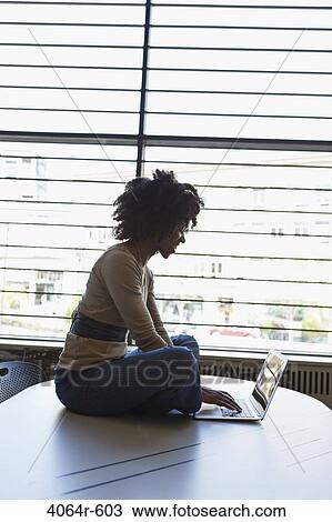Stock Image - Businesswomen using laptop on table in office. Fotosearch