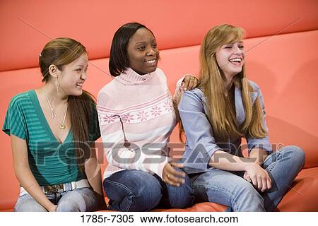 Stock Photography - Cheerful teenage girlfriends sitting together. Fotosearch