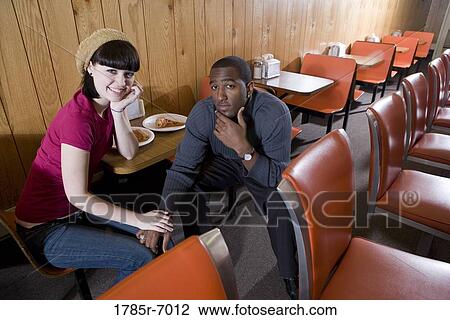 Cheerful young inter-racial couple sitting in a cafe View Large Photo Image Stock Image - Cheerful young inter-racial couple sitting in a cafe. Fotosearch