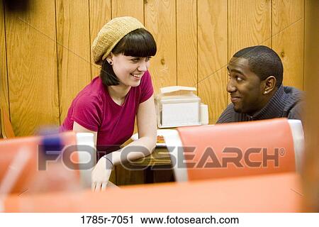 Stock Image - Cheerful young inter-racial couple sitting in a cafe. Fotosearch