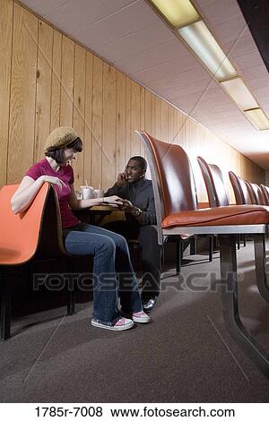 Stock Photo - Cheerful young inter-racial couple sitting in a diner. Fotosearch