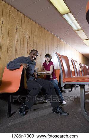 Stock Photo - Cheerful young inter-racial couple sitting in a diner. Fotosearch