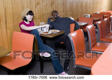 Cheerful young inter-racial couple sitting in a pizza parlor View Large Photo Image Stock Photograph - Cheerful young inter-racial couple sitting in a pizza parlor. Fotosearch