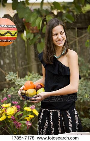 Cheerful young woman holding a bowl of fruit View Large Photo Image Stock Photo - Cheerful young woman holding a bowl of fruit. Fotosearch