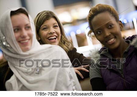Stock Image - Cheerful young women sitting together. Fotosearch