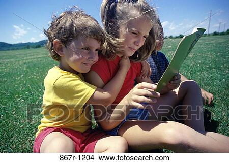 Children sitting on a lawn reading a book View Large Photo Image Picture - Children sitting on a lawn reading a book. Fotosearch