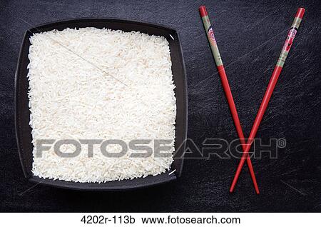 Close-up of a bowl of uncooked rice with chopsticks View Large Photo Image Stock Image - Close-up of a bowl of uncooked rice with chopsticks. Fotosearch