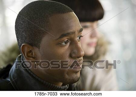 Stock Image - Close-up of a contemplative young inter-racial couple. Fotosearch