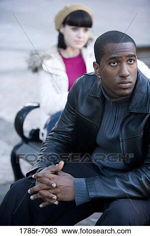 Close-up of a contemplative young inter-racial couple on a park bench View Large Photo Image Stock Image - Close-up of a contemplative young inter-racial couple on a park bench. Fotosearch