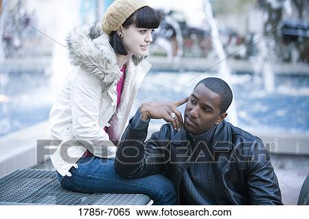 Stock Photography - Close-up of a contemplative young inter-racial couple on a park bench. Fotosearch