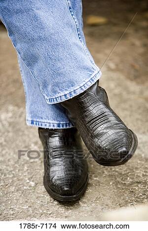 Picture - Close-up of a man's feet in blue jeans and cowboy boots. Fotosearch