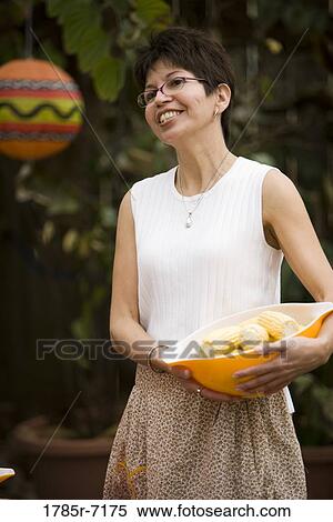 Stock Photography - Close-up of a mature woman carrying a bowl of corn. Fotosearch