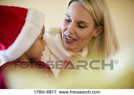 Stock Photo - Close-up of a mother with her daughter wearing Santa hat. Fotosearch
