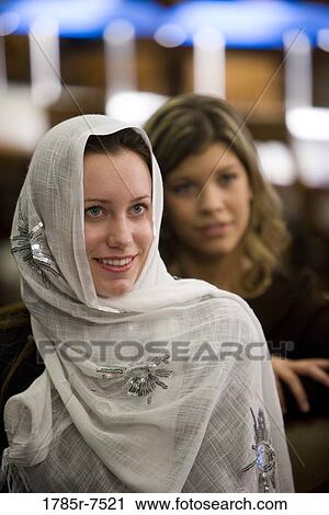 Close-up of a smiling young woman wearing a head scarf, another woman in the background View Large Photo Image Stock Image - Close-up of a smiling young woman wearing a head scarf, another woman in the background. Fotosearch