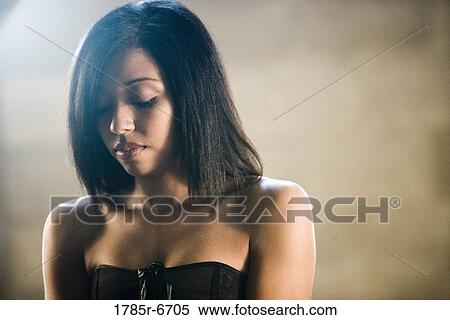 Stock Photography - Close-up of a young woman in a black dress looking downwards. Fotosearch