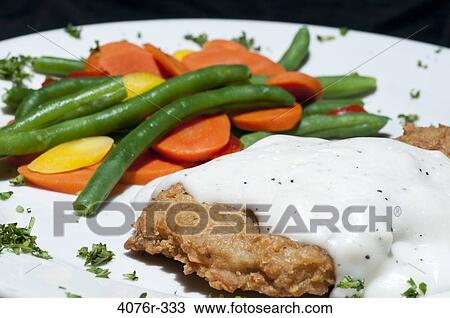 Stock Image - Close up of fried chicken with veggies. Fotosearch