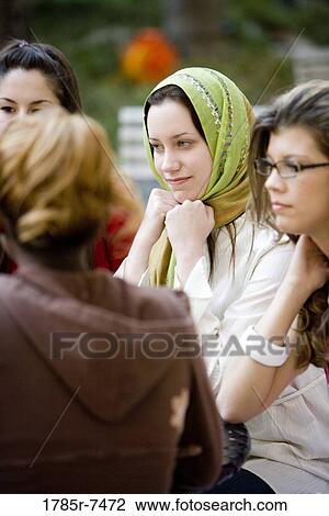Close-up of girlfriends sitting together conversing View Large Photo Image Stock Image - Close-up of girlfriends sitting together conversing. Fotosearch