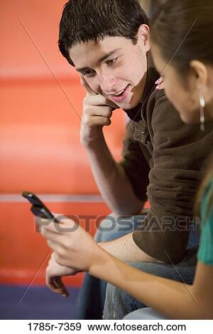 Close-up of teenage friends looking at cellphone View Large Photo Image Stock Photo - Close-up of teenage friends looking at cellphone. Fotosearch