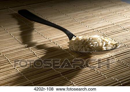 Stock Photo - Close-up of uncooked rice in a spoon. Fotosearch
