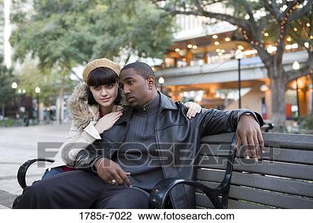 Contemplative young inter-racial couple sitting on a park bench View Large Photo Image Stock Image - Contemplative young inter-racial couple sitting on a park bench. Fotosearch