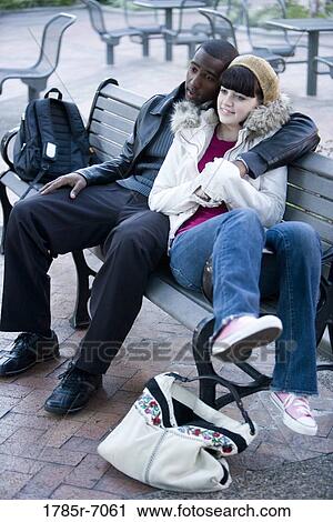 Contemplative young inter-racial couple embracing on a park bench View Large Photo Image Stock Image - Contemplative young inter-racial couple embracing on a park bench. Fotosearch