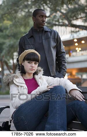 Stock Photograph - Contemplative young inter-racial couple at a city park. Fotosearch