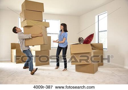 Stock Photo - Couple moving into new house, man carrying several boxes about to fall. Fotosearch
