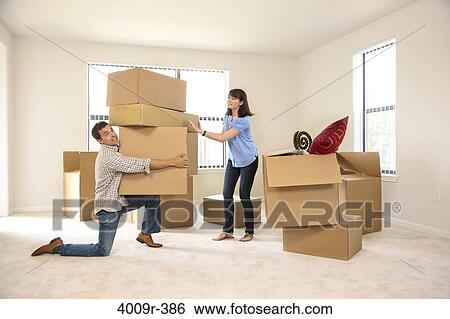 Stock Photograph - Couple moving into new house, man carrying several boxes. Fotosearch