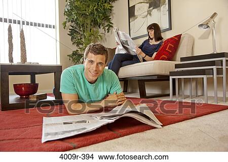 Picture - Couple relaxing at home, reading newspaper. Fotosearch