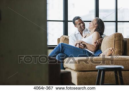 Couple relaxing on couch in loft apartment View Large Photo Image Stock Photo - Couple relaxing on couch in loft apartment. Fotosearch