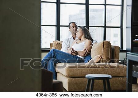 Couple relaxing on couch in loft apartment View Large Photo Image Stock Photograph - Couple relaxing on couch in loft apartment. Fotosearch