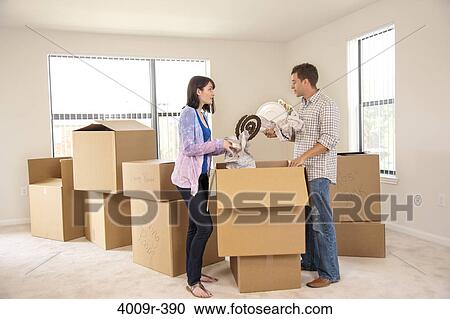 Stock Image - Couple unpacking their belonging as they move into new house. Fotosearch