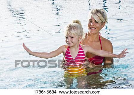 Picture - Cute little girl and mom having fun in pool. Fotosearch