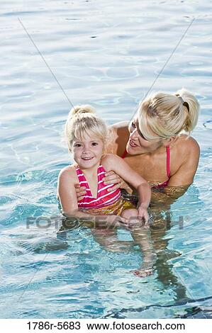Stock Image - Cute little girl and mom having fun in pool. Fotosearch