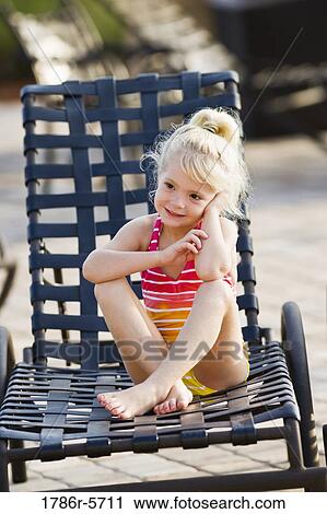 Stock Image - Cute little girl sitting in lounge chair. Fotosearch