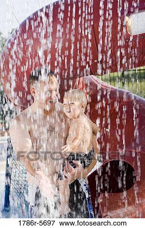 Dad holding son under shower of water drops View Large Photo Image Stock Photo - Dad holding son under shower of water drops. Fotosearch