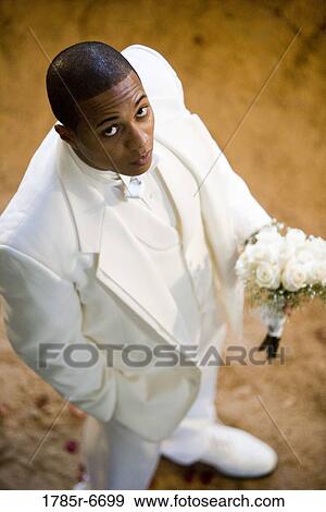 Elevated view of a groom in a white tuxedo holding a bouquet of white roses View Large Photo Image Stock Photo - Elevated view of a groom in a white tuxedo holding a bouquet of white roses. Fotosearch