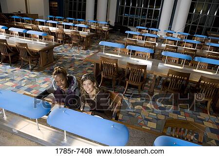 Elevated view of two women students sitting in the reading room of a library View Large Photo Image Stock Photo - Elevated view of two women students sitting in the reading room of a library. Fotosearch