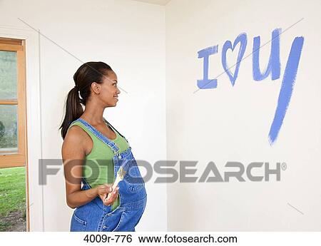 Stock Photograph - Expectant mother preparing nursery, painting. Fotosearch