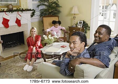 Family in pajamas sitting in living room decorated for Christmas View Large Photo Image Stock Image - Family in pajamas sitting in living room decorated for Christmas. Fotosearch