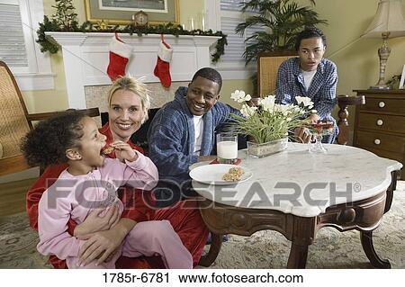 Family in pajamas sitting in living room decorated for Christmas View Large Photo Image Stock Image - Family in pajamas sitting in living room decorated for Christmas. Fotosearch