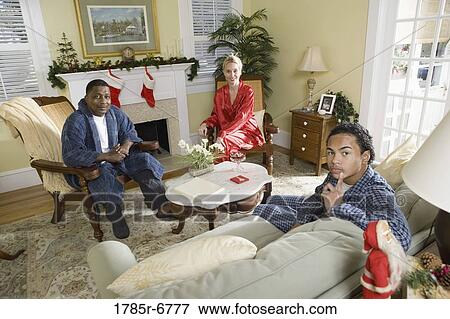 Family in pajamas sitting in living room decorated for Christmas View Large Photo Image Stock Photo - Family in pajamas sitting in living room decorated for Christmas. Fotosearch