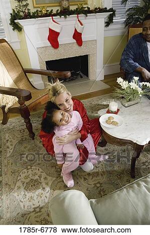Family in pajamas sitting in living room decorated for Christmas View Large Photo Image Stock Photo - Family in pajamas sitting in living room decorated for Christmas. Fotosearch