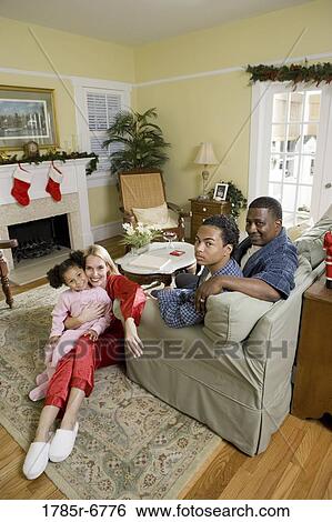 Family in pajamas sitting in living room decorated for Christmas View Large Photo Image Stock Photograph - Family in pajamas sitting in living room decorated for Christmas. Fotosearch