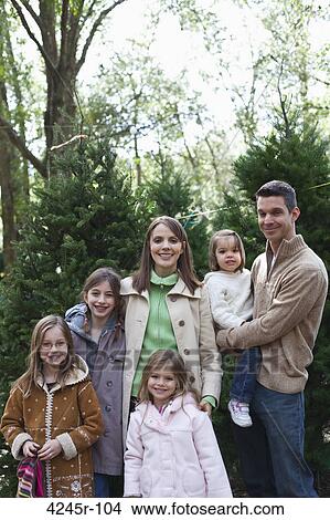 Picture - Family standing near a Christmas tree. Fotosearch