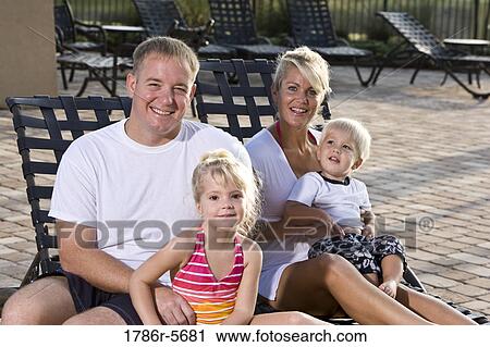Stock Image - Family with two children on pool lounge chairs. Fotosearch