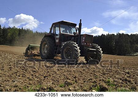 Stock Image - Farmer plowing field with tractor, Bavaria, Germany. Fotosearch